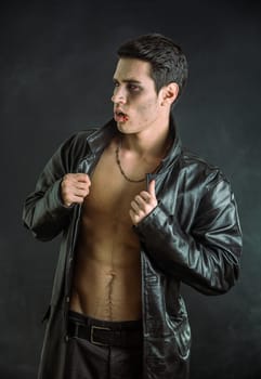 A shirtless man in a black leather jacket in a vampire look. Photo of a young and handsome vampire in a stylish black leather jacket