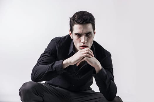 A man wearing a necklace with blood on his face. Photo of a handsome young man with blood on his face wearing a vampire necklace