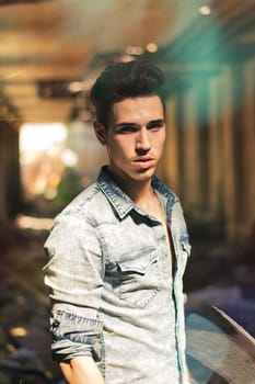 A man standing in an alley with his hands in his pockets in an abandoned building, looking at camera