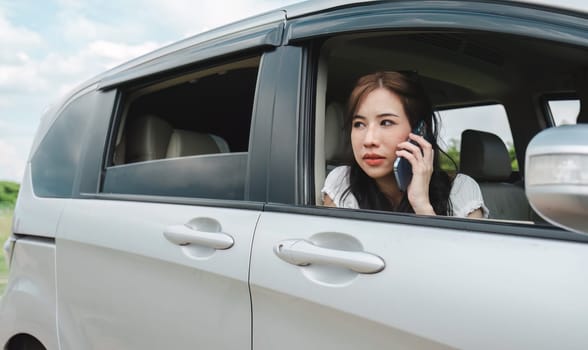 Stressed and confused Asian woman calls insurance on faulty car while traveling together.