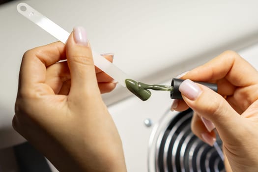 A manicurist applies gel nail polish to empty tips as a sample for future clients. Large range of gel polishes. Spa body care concept. Nail technician