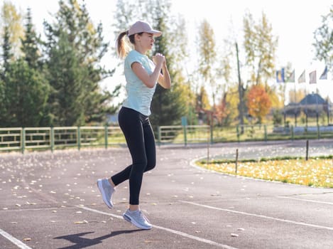 A young beautiful woman in sportswear plays sports at a local stadium. Exercise, jog and exercise at the beginning of the day. Healthy and active lifestyle.