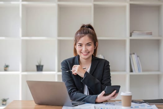 Businesswoman using calculator for do math finance on wooden desk in office and business working background, tax, accounting, statistics and analytic research concept.