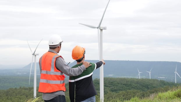 Engineer with his son on a wind farm atop a hill or mountain in the rural. Progressive ideal for the future production of renewable, sustainable energy. Energy generation from wind turbine.