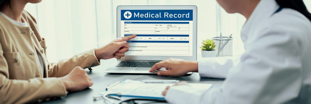 Doctor show medical diagnosis report on laptop and providing compassionate healthcare consultation while being supportive and holding young patient hand in doctor clinic office. Neoteric
