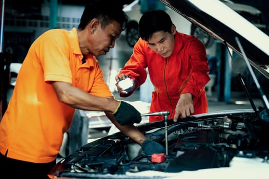 Automotive service mechanic inspect and diagnose car engine issue, repairing and fixing problem in garage workshop. Technician car care maintenance working on internal components of vehicle. Oxus