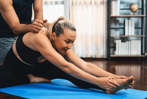 Happy active senior couple in sportswear being supportive and assist on yoga posture together at home. Healthy senior man and woman lifestyle with yoga exercise. Clout