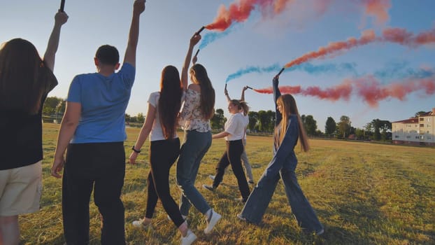 A group of friends spraying multi-colored smoke at sunset