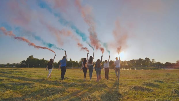 A group of friends spraying multi-colored smoke at sunset