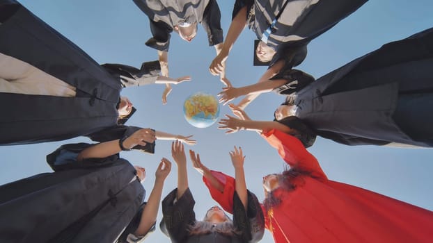 College alumni students toss a globe of the world into the sky