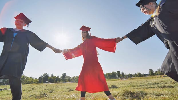 College graduates holding hands run in a round dance