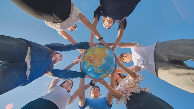 Friends holding a geographical globe in their hands. The concept of keeping the world safe