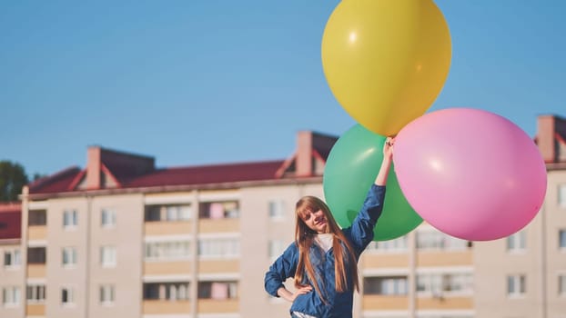 A girl happily poses with large with colorful balloons in the city