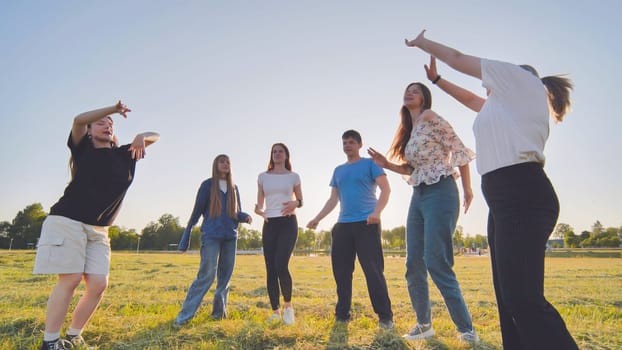 Funny jolly friends dancing in the city meadow in the evening