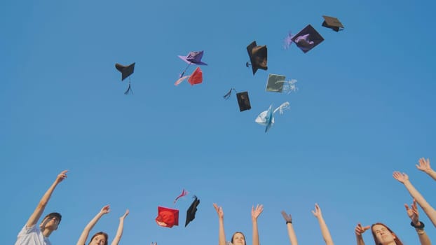 Graduates tossing multicolored hats against a blue sky