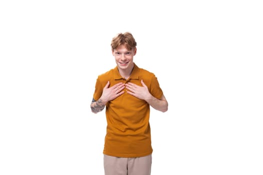 young caucasian man with red hair is dressed in a yellow t-shirt on a studio background.