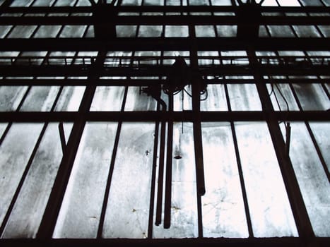 Glass front of an old and abandoned industrial hall from the inside (color photo)