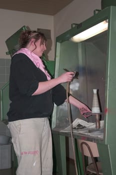 Vocational school student painting a porcelain container with spraying technique
