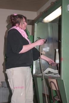 Vocational school student painting a porcelain container with spraying technique