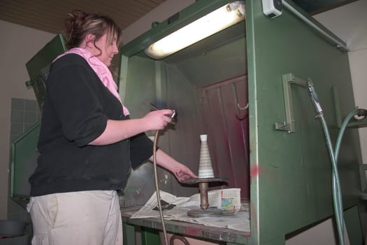 Vocational school student painting a porcelain container with spraying technique