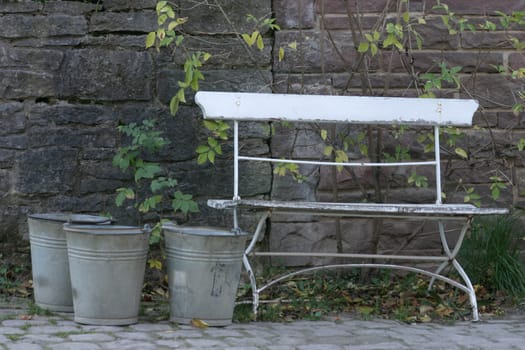 Three tin buckets next to a garden bench