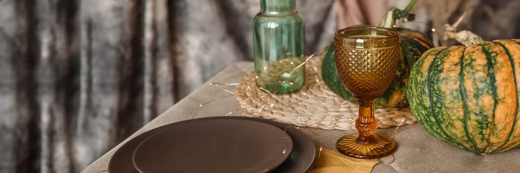 Autumn interior: a table covered with dishes, pumpkins, a relaxed composition of Japanese pampas grass. Interior in the photo Studio. Close - up of a decorated autumn table