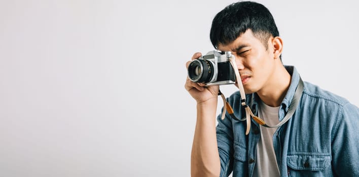A professional photographer captures the essence of a young man's charisma with a vintage camera. Studio shot isolated on white background. The picture is pure paparazzi magic