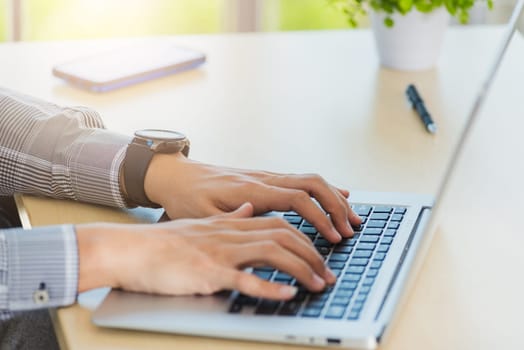 Asian businessman working on his laptop computer with blank copy space screen he typing on keyboard at home office desk. The man play social media on computer table