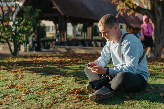 Professional photographer taking picture of beautiful autumn park. man professional photographer sit with camera in autumn park