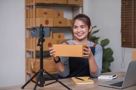 Asian blogger review products and video camera on her phone, sell them online, and showcase her products online on social media. ecommerce business live streaming vlog new normal concept.