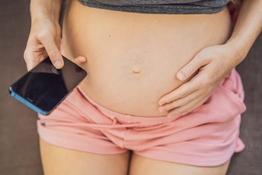 Pregnant girl with a smartphone. The concept of a negative impact on the unborn child in the womb. Violation of the nervous system of the child, reproductive.