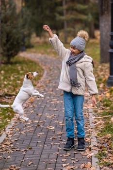 Caucasian girl playing with a dog for a walk in the autumn park