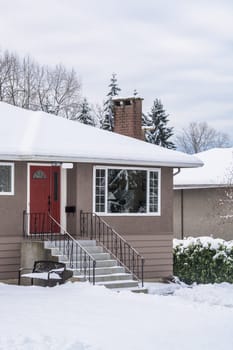 Entrance of residential house with front yard in snow. Family house on winter cloudy day