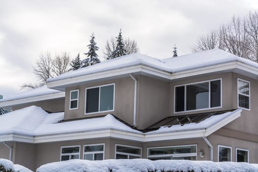 Top of residential house in snow on winter cloudy day