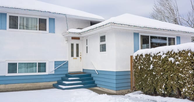 Family residential house with front yard in snow. Beautiful North American house on winter cloudy day