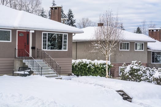 Street of family houses and front yards in snow. North American houses on winter cloudy day