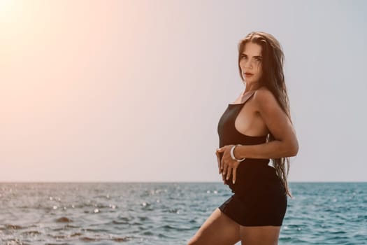 Woman travel sea. Young Happy woman in a long red dress posing on a beach near the sea on background of volcanic rocks, like in Iceland, sharing travel adventure journey