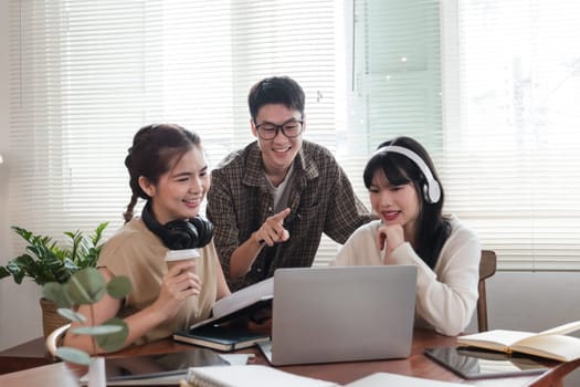 A cheerful and intelligent young Asian man is standing and sharing his thoughts in a meeting with his team. University students, friendship, startups, teamwork.