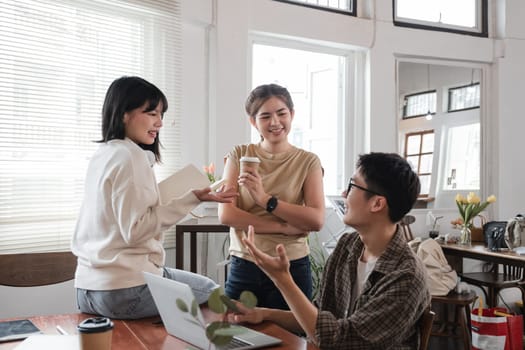 A cheerful and smart young Asian female is standing and sharing her ideas in a meeting with her team. University students, friendship, startups, teamwork.