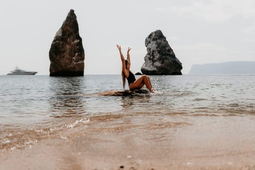 Woman travel sea. Young Happy woman in a long red dress posing on a beach near the sea on background of volcanic rocks, like in Iceland, sharing travel adventure journey