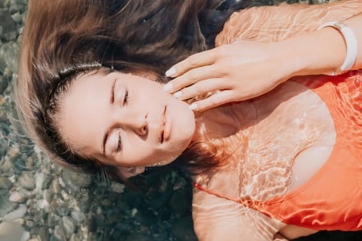 Side view a Young beautiful sensual woman in a mint long dress posing on a volcanic rock high above the sea during sunset. Girl on the nature on overcast sky background. Fashion photo