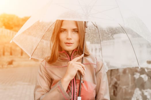 Woman rain park. Happy woman portrait wearing a raincoat with transparent umbrella outdoors on rainy day in park near sea. Girl on the nature on rainy overcast day