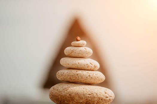 Pyramid stones on the seashore with warm sunset on the sea background. Happy holidays. Pebble beach, calm sea, travel destination. Concept of happy vacation on the sea, meditation, spa, calmness.