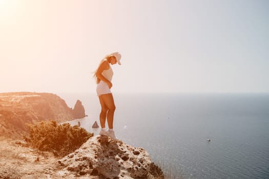 Woman travel sea. Young Happy woman in a long red dress posing on a beach near the sea on background of volcanic rocks, like in Iceland, sharing travel adventure journey