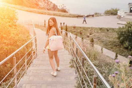 Woman travel sea. Happy tourist taking picture outdoors for memories. Woman traveler looks at the edge of the cliff on the sea bay of mountains, sharing travel adventure journey.