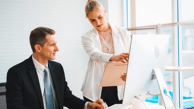 Two business people talk project strategy at office meeting room. Businessman discuss project planning with colleague at modern workplace while having conversation and advice on financial report. Jivy