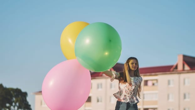 A girl happily poses with large with colorful balloons in the city