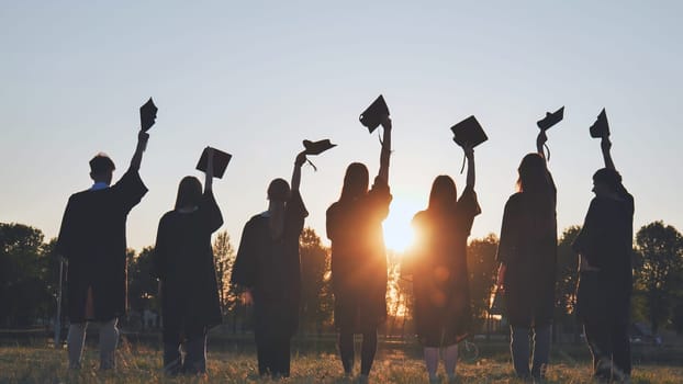 Silhouette of fresh graduates throwing their motarboard or trencher up in the air after their graduation