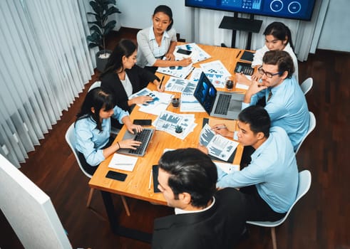 Diverse group of business analyst team analyzing financial data report. Finance data analysis chart and graph dashboard show on TV screen in meeting room for strategic marketing planning. Habiliment