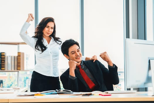 Two happy business people celebrate at office meeting room. Successful businessman congratulate project success with colleague at modern workplace while having conversation on financial report. Jivy